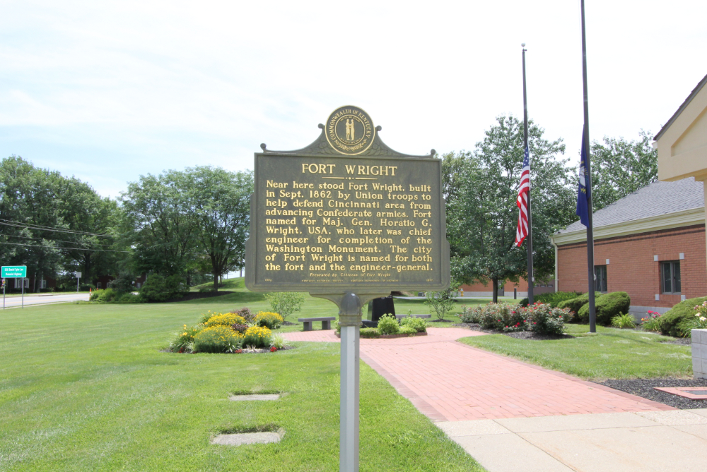 Bronze Fort Wright historical marker on a lawn with flags, brick path, and a surrounding park area, detailing Civil War history.